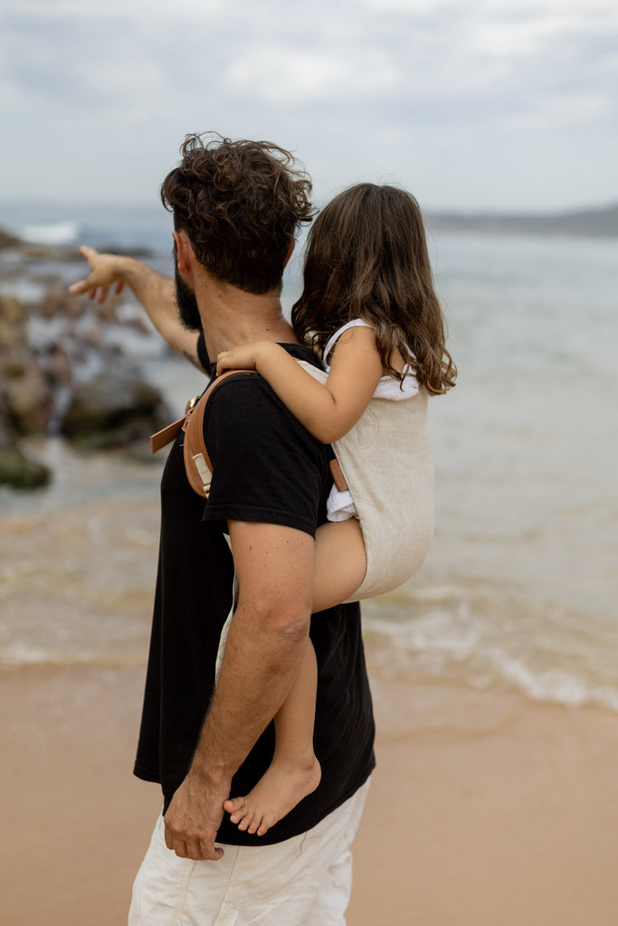 Dad carrying toddler in natural Mamatoto Nomad baby carrier at the beach — best toddler carrier in Australia for comfort and support
