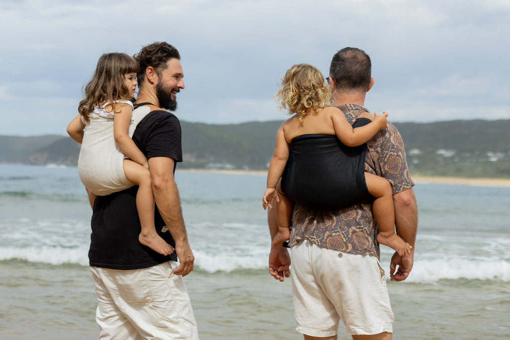 Two fathers babywearing with Mamatoto Nomad carriers in natural and black — ergonomic baby carriers for dads in Australia.